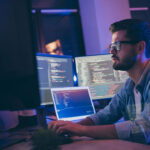 Profile side view portrait of man typing in dark room